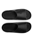 Pair of black slides on a white background with Close-up of men’s foot resting in the deep footbed for everyday comfort .