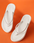 Top-down view of Chupps Solis pair with glitter-detailed V-straps and soft footbed on an orange background