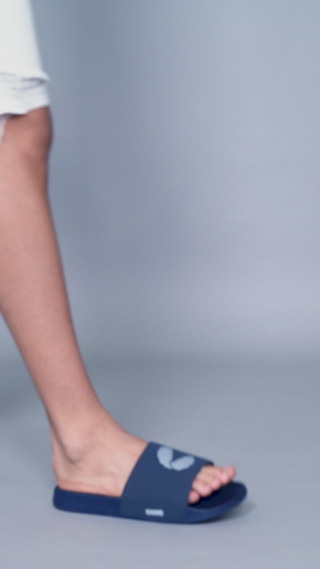 Young men in casual settings wear navy blue men’s sliders with shorts and tattered denims, highlighting versatile styling and comfort across various Chupps slider designs.